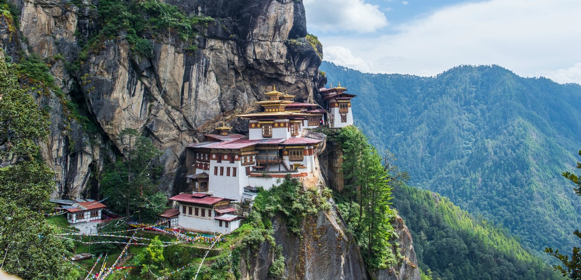 The Taktsang Monastery at Paro perched on the edge of a cliff, with more mountains in the background